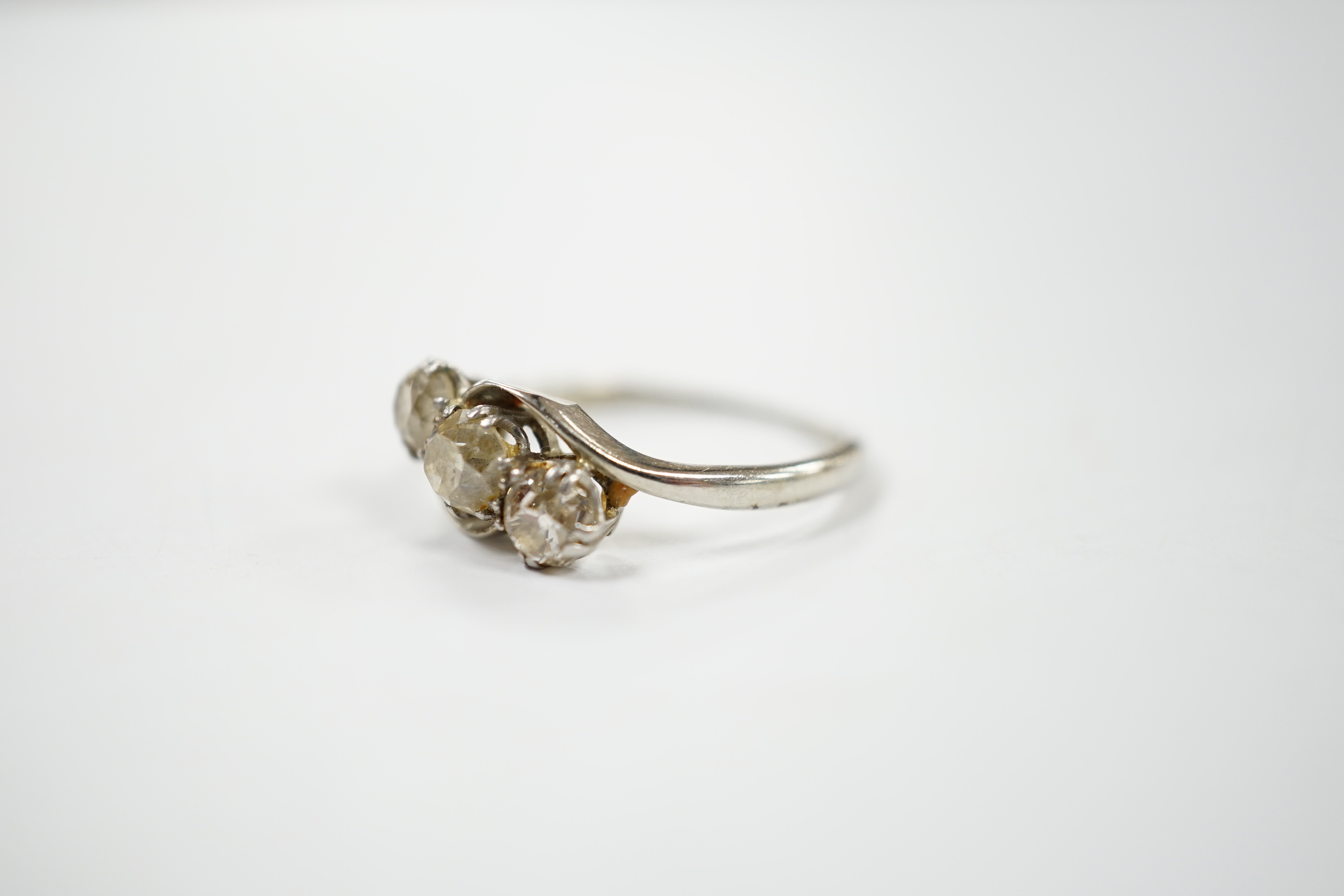 An 18ct, plat and three stone old mine cut diamond set crossover ring, size N, gross weight 2.3 grams.